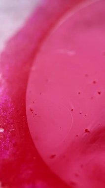 Dikey video. Parlak mürekkep. Boya sıçraması. Işıldayan sıvı. Odaklanmamış pembe beyaz gümüş rengi lüks jel yağ kabarcıkları ıslak parlak doku soyut sanat arkaplanı.