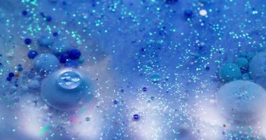 Işıldayan akış. Akrilik baloncuk. Parıldayan parçacıklar renkli boya karışımı. Mavi gökkuşağı sızıntısı yüzey suyu soyut arkaplan.