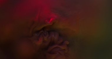 Mistik boya. Parıltı yayılıyor. Kırmızı turuncu kahverengi parlak toz, koyu su yüzeyinde ortaya çıkar. Parlak dumanlı sıvı karışımı soyut arkaplan.