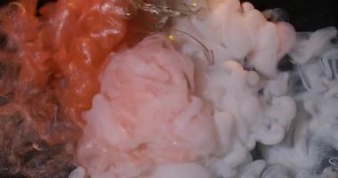 Duman patladı. Boya karışımı. Parlak turuncu mat beyaz sanat sıvısı akıntıları. Kırık ampulün üzerinde çakışan dumanlı mürekkep spreyi..