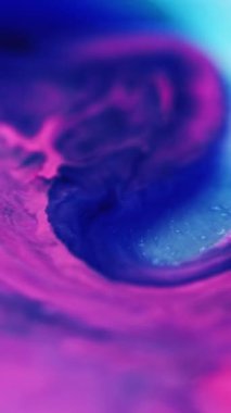 Dikey video. Parlak sıvı karışımı. Boya dökülmüş. Odaklanmamış pembe renk parıldayan parçacıklar sıvı emülsiyon akış hareketini soyut sanat arka planı.