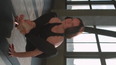 Dikey video. Yoga pratiği. Denge çalışması. Spor elbiseli bir kadın spor salonunda spor salonunda spor salonunda jimnastik egzersizi yaparken amuda kalkma kurbağası pozu veriyor..