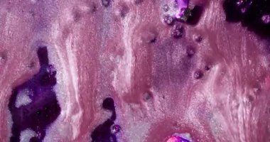 Mürekkep döküldü. Parlak lekeler. Soyut arkaplanda hareket eden suda pembemsi pembe pigment sıvı yağ damlası boya akışı.