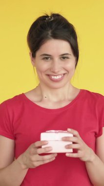 Dikey video. Kötü bir hediye. Heyecanlı kadın hayal kırıklığına uğradı. Boks hediyesini açmaktan sıkıldı. Üzücü duygularını sarı renkte ifade ediyor..