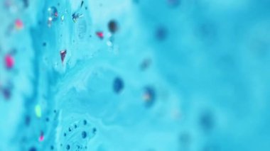Dikey video. Akrilik sıvı dalga. Boya baloncukları. Odaklanmamış mavi renk metalik folyo simli pullu parçacıklar mürekkep sıvısı boya pigment karışımı akış hareketi soyut sanat arkaplanı.