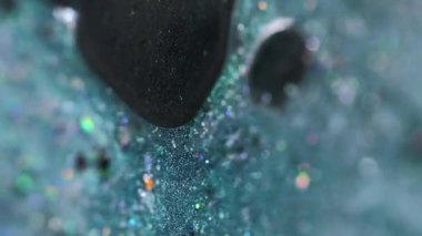 Dikey video. Parlak mürekkep damlası. Boya dökülmüş. Bulanık deniz mavisi siyah holografik pullu parçacıklar yağ jeli sıvı emülsiyon soyut sanat arka planı ve bokeh ışıkları.