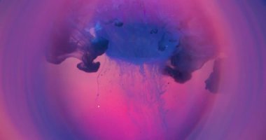 Odaklanamayan damlama. Elmas değerli taş. Kesimli yuvarlak kristalin pembe mor sıvısı düşüyor. Çember neon bulanık mor mavi soyut su arkaplanındaki boya karışımı.