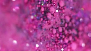 Dikey video. Parıldayan sıvı dökülmüş. Akrilik boya karışımı. Bulanık pembe renkli holografik pullar sıvı mürekkep damlaları emülsiyon hareketli soyut sanat arka planı Bokeh ışıkları.