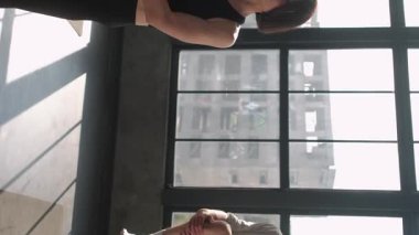 Dikey video. Denge egzersizi. Yoga grubu. Kadın spor eğitmeni olan aktif insanlar meditasyon jimnastik sınıfı ağacıyla iç mekandaki spor salonundaki paspasın üzerinde asana pozu veriyorlar..