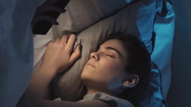 Dikey video. Mobil uykusuzluk. Uykusuzluk. Yorgun, uykulu bir kadın gecenin geç saatlerinde karanlık bir yatak odasında telefonla uyuyakalıyor..