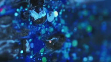 Dikey video. Akrilik boya karışımı. Islak sim dökülmüş. Odaklanmamış mavi renk ışıltılı pullu parçacıklar su sıvısı parlatıcı emülsiyon mürekkep damlası hareket soyut sanat arka planı.