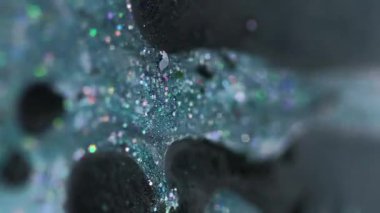 Dikey video. Sıvı sim dökülmüş. Mürekkep sıvısı. Bulanık deniz mavisi siyah holografik pullu parçacıklar boya damlaları emülsiyon jel damlaları hareketli soyut sanat arka planı Bokeh ışıkları.