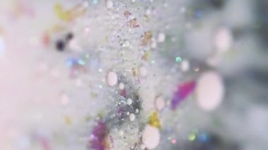 Dikey video. Parlak sıvı damlası. Parlak parlatıcı. Bulanık beyaz renk yanardöner pullar mürekkep damlaları sıvı dökülme hareketli soyut sanat arka planı ve bokeh ışıkları.