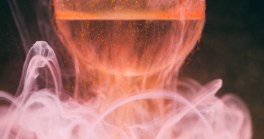 Duman sıçratma boyası. Top arka planda. Odaklanmamış turuncu pembe renkli su yuvarlak dokuma sıvısı soyut kara sanat dalgasıyla.