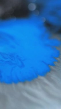 Dikey video. Boya dökülmüş. Bulanık akrilik leke. Odaklanmamış mavi siyah renk ıslak leke sıçrayan sıvı leke yayılan dalga hareketi soyut sanat arkaplanı.