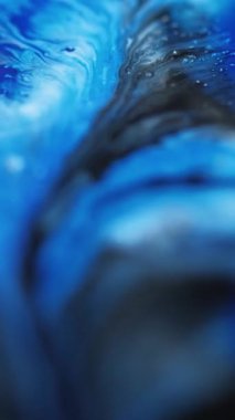 Dikey video. Boya damlası. Akışkan sanat. Bulanık mavi, parlak, akrilik, sıvı, dökülme, dalga, hareket, mermer desen soyut arka plan..