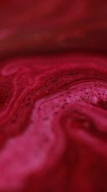 Dikey video. Parlak sıvı karışımı. Boya dökülmüş. Odaklanmamış kırmızı pembe renk parıldayan parçacıklar sıvı emülsiyon akış hareketini soyut sanat arkaplanı.