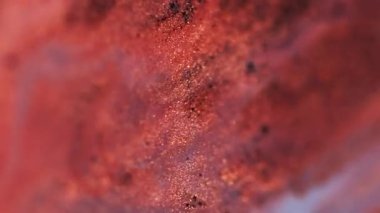 Parlak boya sıvısı. Jel gölgeleri. Parlak sıvı. Odaklanmamış kırmızı renk parıldayan pullu parçacıklar su sıvısı emülsiyonunda titreşiyor soyut sanat arka planında Bokeh ışıkları ile birlikte salınıyor..