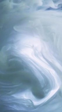Dikey video. İpek bulut. Duman girdabı. Odaklanmamış mavi beyaz renkli parlayan sis yüzen boya, su karışımı hareket eden ruhani soyut sanat arka planı..