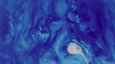 Yağ akışı. Bulanık parıltı dokusu. Parıldayan mavi beyaz parçacıklar boya damlası dalgası soyut sanat arka planına düşüyor.