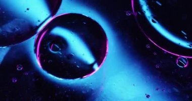 Kozmetik özü. Neon kabarcığı. Soyut ışık arka planında yüzen mavi mor renkli moleküler damlalar..