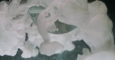 Sis boyası. Küre damlıyor. Odaklanmamış beyaz renk dokusu tozu soyut koyu siyah arkaplan üzerinde yüzen şeffaf yuvarlak sıçratır.