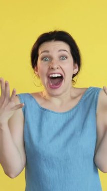 Dikey video. Ne hoş bir sürpriz. Şaşırtıcı bir ifade. Heyecanlı mutlu kazanan kadın el çırpıyor zafer kutlamasının tadını çıkarıyor sarı boş alanda tek başına..