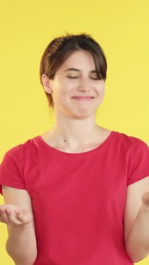 Dikey video. Destekleyici jest. Neşeli kadın. Sarı arka planda izole edilmiş, mutlu, mutlu, mutlu bir alkış..