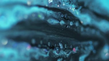 Dikey video. Parlak bir dökülme. Akrilik boya. Odaklanmamış mavi renkli holografik simli parçacıklar yüzen baloncuklar boya sıvı karışımı akış hareketi soyut sanat arka planı.