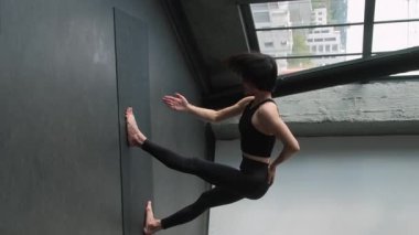 Dikey video. Spor dersi. Yoga seansı. Bayan fitness eğitmeni, beden egzersizleri, kapalı spor salonundaki Asya duruşunun düzeltilmesine yardımcı oluyor..