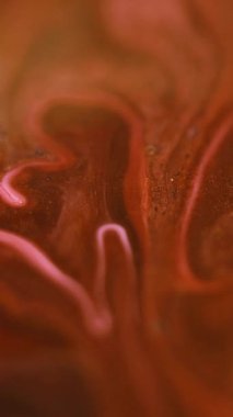 Dikey video. Parlak sıvı karışımı. Boya dökülmüş. Odaklanmamış altın rengi parıldayan parçacıklar sıvı emülsiyon akış hareketini soyut sanat arka planı.