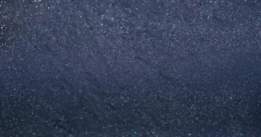 Işıldayan sıvı. Parlak yüzey. Gri gümüş çözünmüş akış, parlak metal parçacıkları dökülüyor. Parlak akış dokusu soyut arkaplan.