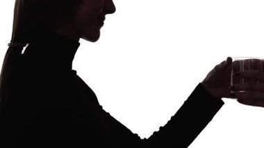 Mineral içeceği. Su dengesi. Koyu mavi parıltılı ışıltı çift pozlama profil silueti tatmin olmuş bir kadın beyaz kopya alanı arka planında cam alıyor.