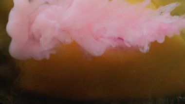 Sıvı patlaması. Puf boyası. Pembe buhar akışı kahverengi turuncu resim sıvısının içine düşer. Etkisiz hale getirilmiş renkli su soyut arkaplanı.