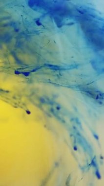 Dikey video. Su karışımı boya. Sis girdabı. Odaklanmamış mavi sarı renk parlayan sis dokusu dönen dalga hareket eden soyut sanat arkaplanını ortaya çıkarıyor.