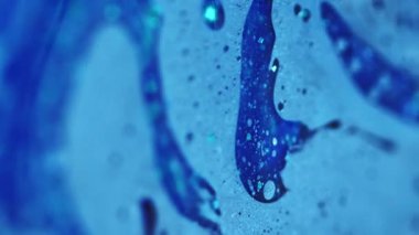 Dikey video. Mürekkep akışı. Banyo köpüğü dokusu. Odaklanmamış mavi renkli parlak partiküller yağlı baloncuk sıvısı emülsiyon sıvı damlama hareket soyut sanat arka planı.