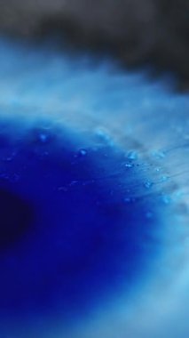 Dikey video. Boya lekesi. Mürekkep damlası. Odaklanmamış mavi renk ıslak leke ışıl ışıl parçacıklar sıvı dökülmesi hareketli soyut sanat arkaplanı ortaya çıkardı.