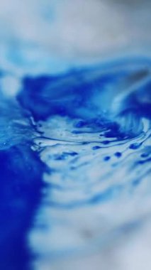 Dikey video. Mürekkep döküldü. Sıvı karışımı. Odaksız mavi beyaz renk ıslak akrilik emülsiyon karışık dalga akış mermer desen soyut sanat arka planı.