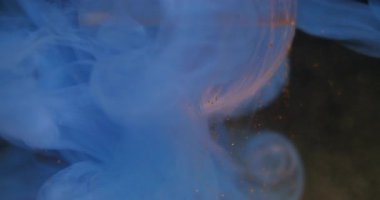 Parçacıklar düşüyor. Damla mürekkebi dumanı. Odaklanmamış mavi neon rengi su tozu soyut koyu siyah arkaplan üzerinde yüzen doku.