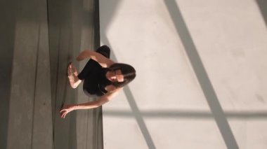 Dikey video. Esneme esnekliği. Denge yogası. Spor salonundaki spor elbiseli kadın amuda kalkma egzersizi asana, spor salonundaki spor paspası üzerine jimnastik yapıyor..