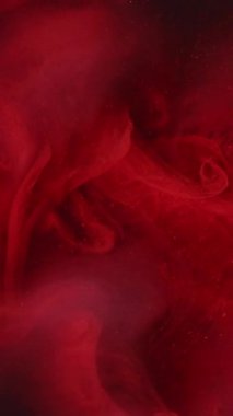 Dikey video. Buhar mürekkebi. Renkli su. Kırmızı duman akışı sisi karışık boya dalgaları soyut duman gizemli sanat kimya arka planında parlayan parçacıklar.