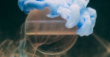 Su mürekkebi dumanı. Küre dokusu. Odaklanmamış mavi boya kokusu soyut sanatın koyu siyah zeminine geometrik yuvarlak sıvı sıçratır.