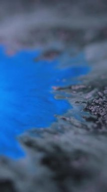 Dikey video. Boya sıçraması. Islak lekeler. Odaklanmamış mavi renk parlak tahıl dokusu akrilik boya karışımı dalga hareketi soyut sanat arkaplanı.