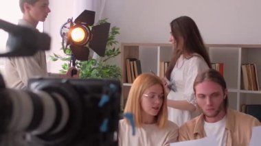 Stüdyo ekibi. Sahne arkası işi. Çeşitli meslektaşlar video çekimi için ışıklandırma ekipmanları hazırlıyor. Profesyonel aydınlatmacılar spot ışıklarını ayarlıyor.