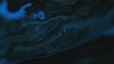 Parıldayan parçacıklar. Boya suyu akışı. Odaklanmamış mavi altın rengi parıldayan toz dokusu mürekkep dalgası hareketi soyut sanat arkaplanı.