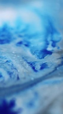 Dikey video. Boya sıçraması. Sıvı dökülmesi. Odaklanmamış mavi renk tahıl dokusu akrilik sıvı karışım damla dalga hareketi soyut sanat arkaplanı.