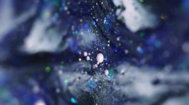 Dikey video. Parlak bir dökülme. Parlak sıvı karışımı. Bulanık mor renkli pırıl pırıl pullu parçacıklar akrilik boya akışkan hareket soyut sanat arka planında Bokeh ışıkları.