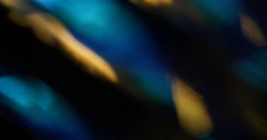 Aydınlatılmış ışık. Bulanık yansıma. Soyut sanat üzerine odaksız sarı mavi yeşil renk deseni, koyu siyah arkaplan.