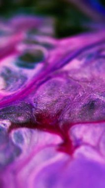 Dikey video. Islak sim dökülmüş. Boya sıçraması. Odaklanmamış mavi pembe renk parıldayan parçacıklar sıvı mürekkep harmanlama hareketi siyah soyut sanat arka planında.