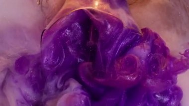 Parıldayan bulut. Boya patlamış. Kırık cam ampulden çıkan mor parlak akarsu çelenk sisli ve soyut arka planda parıldıyor..